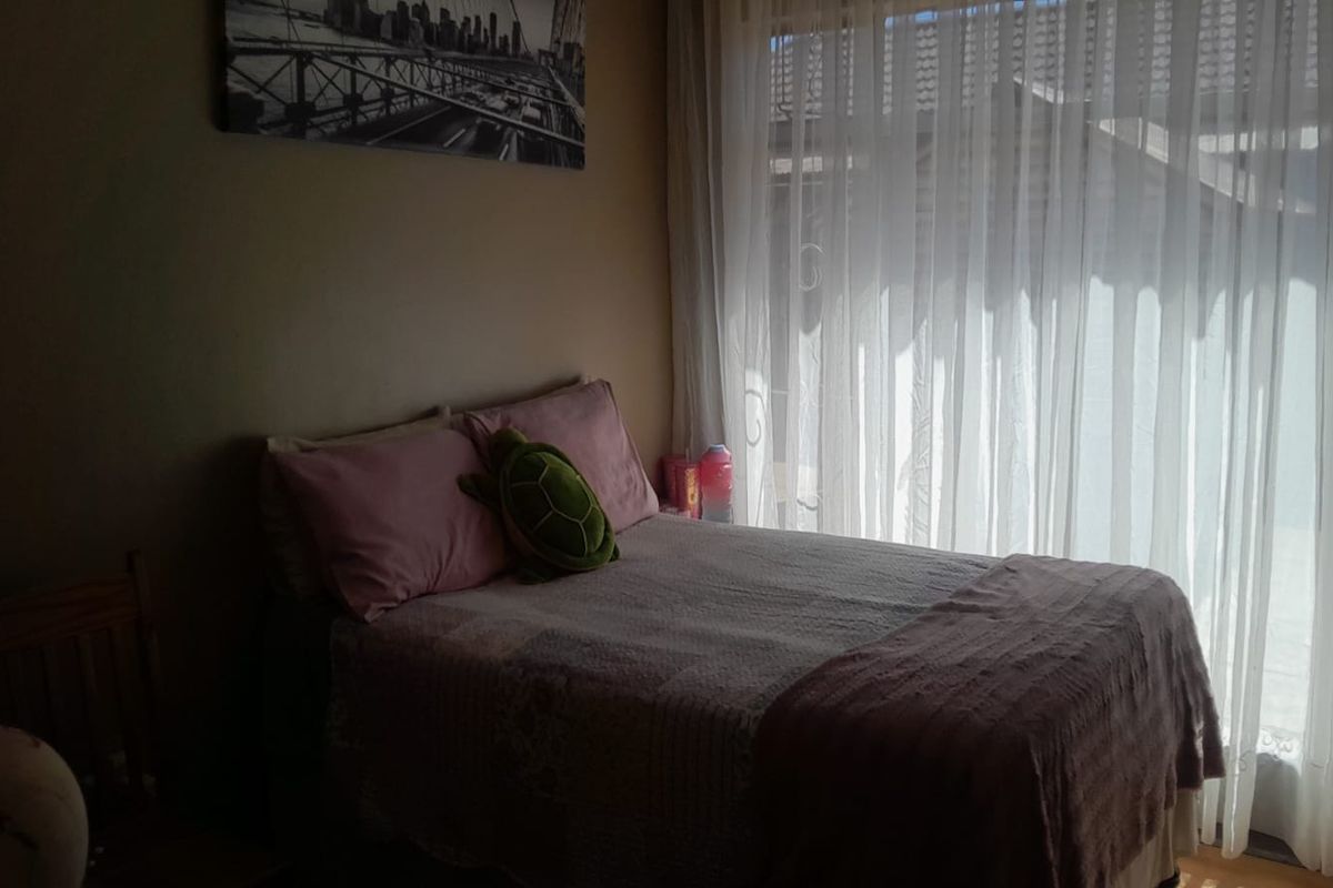 A bedroom featuring large windows with sheer curtains, providing natural light to the space.