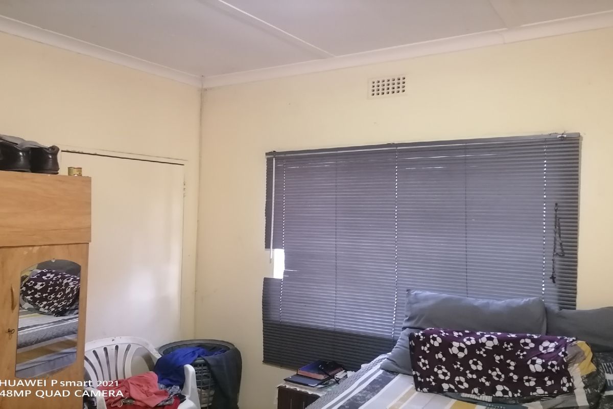 A bedroom featuring a window with damaged blinds, standard interior door, and ceiling ventilation vent.