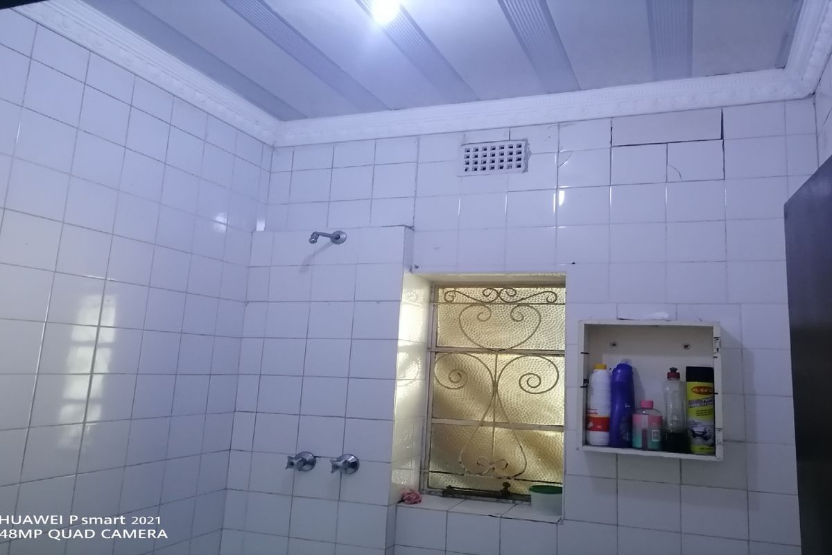 A functional bathroom featuring white wall tiling, a shower head, and a built-in wall niche for storage.