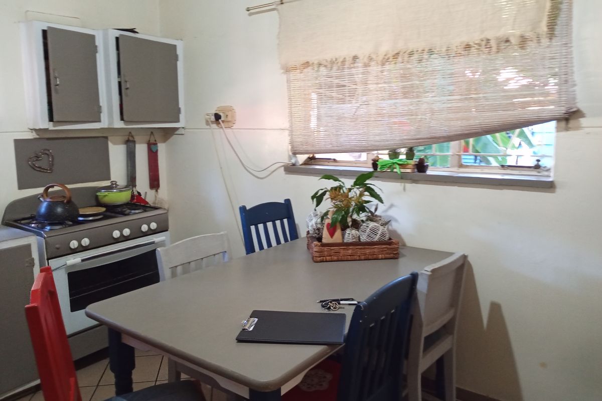 A compact kitchen area featuring built-in cabinetry, a gas stove with oven, and tiled flooring, offering a functional space for meal preparation.