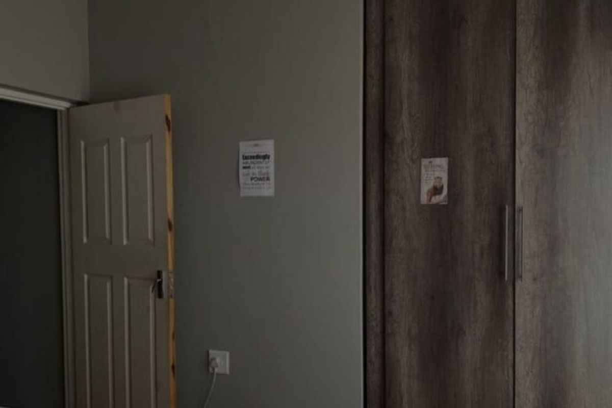 A bedroom featuring wood-look laminate flooring and built-in dark wood-grain wardrobes.