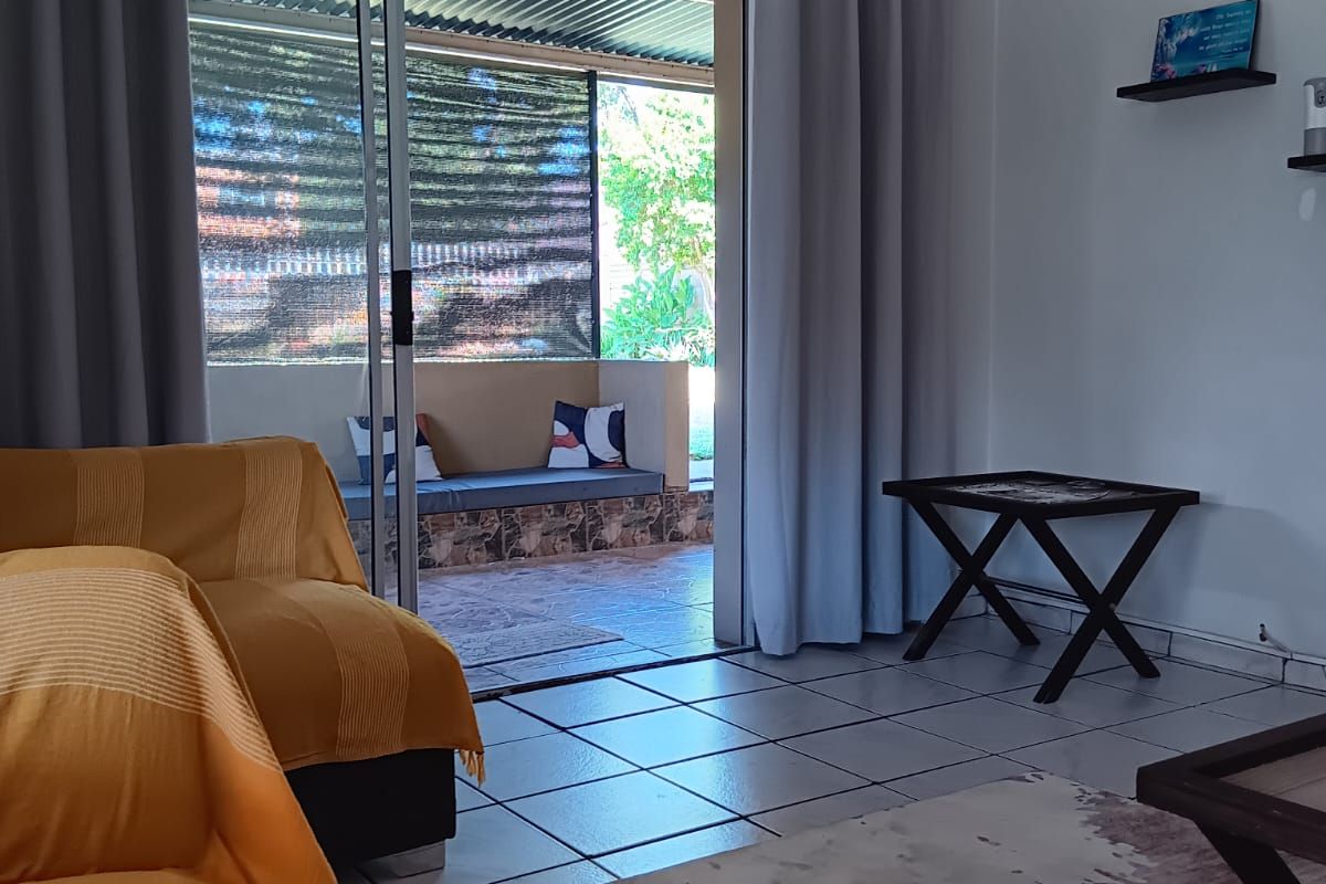 Living room featuring tiled flooring and large sliding glass doors providing direct access to a covered outdoor patio area.