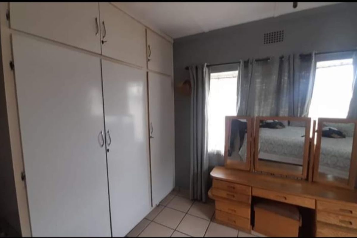 A bedroom featuring built-in floor-to-ceiling cupboards and tiled flooring, offering functional storage space.