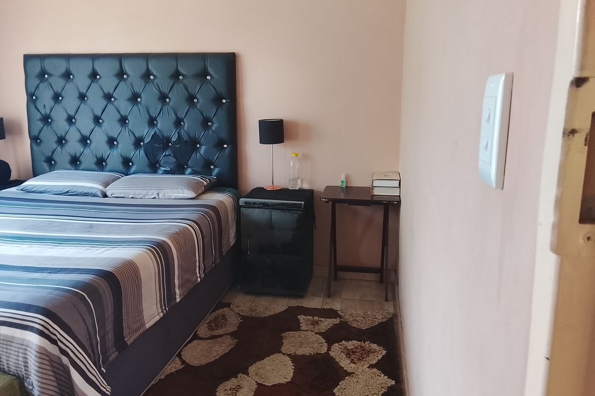 A bedroom featuring tiled flooring and a light-colored wall finish, providing a functional space for rest.