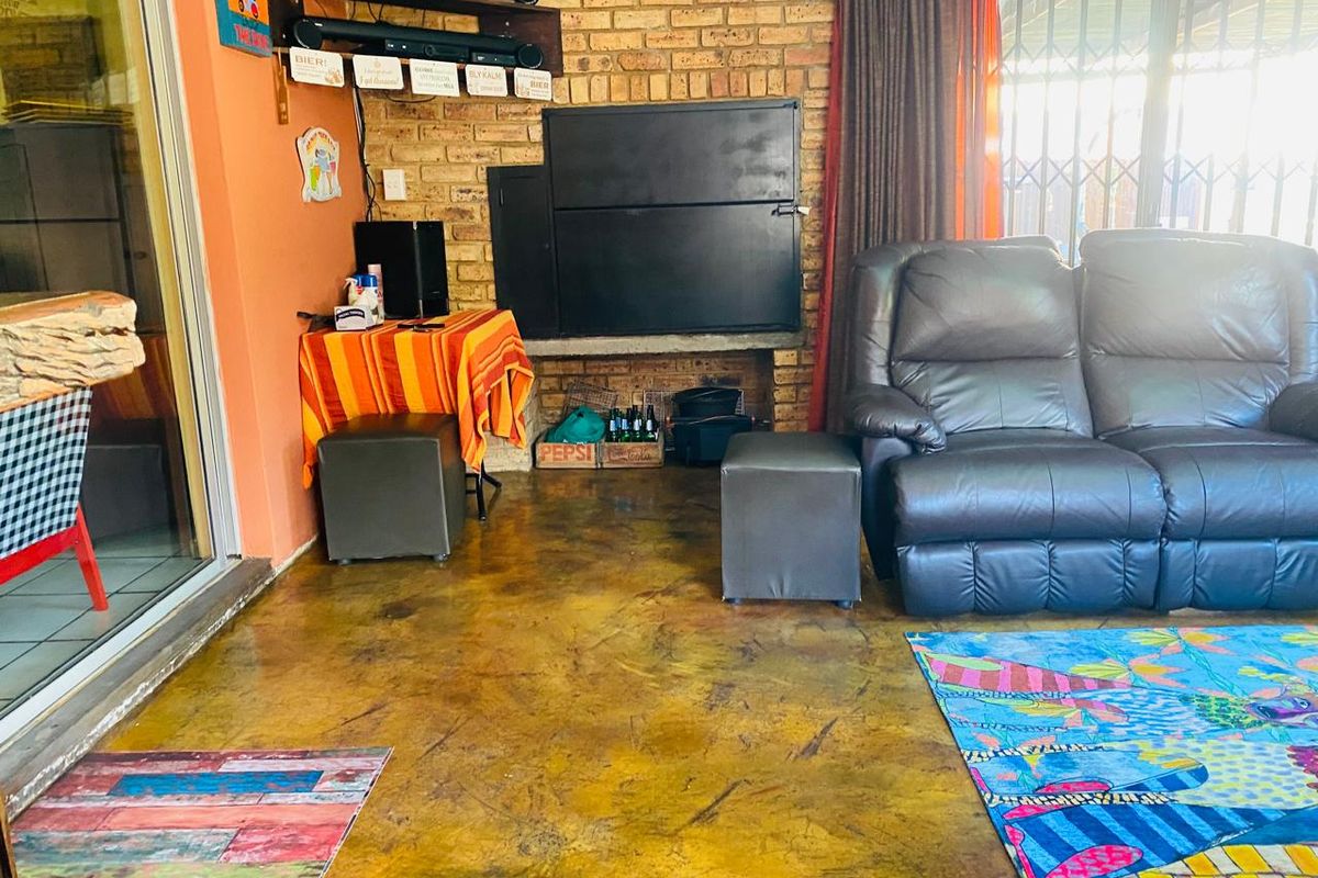 A casual living area featuring a built-in brick fireplace, exposed brick wall, and polished concrete flooring, providing a rustic and functional entertainment space.