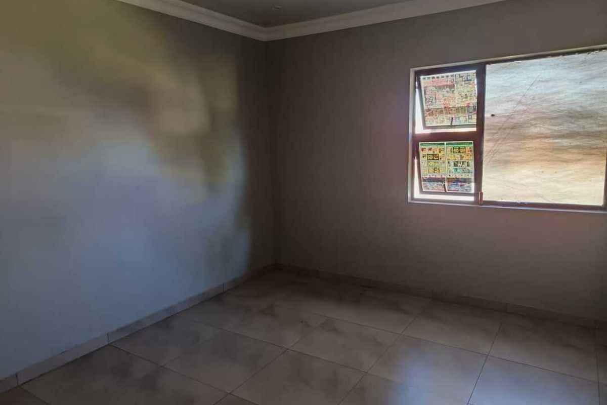 A vacant bedroom featuring neutral tiled flooring and a window with privacy covering, offering a blank canvas for personalization.