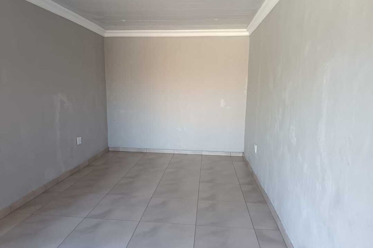 An empty, neutral-toned room featuring tiled flooring and crown molding, providing a blank canvas for personalization.