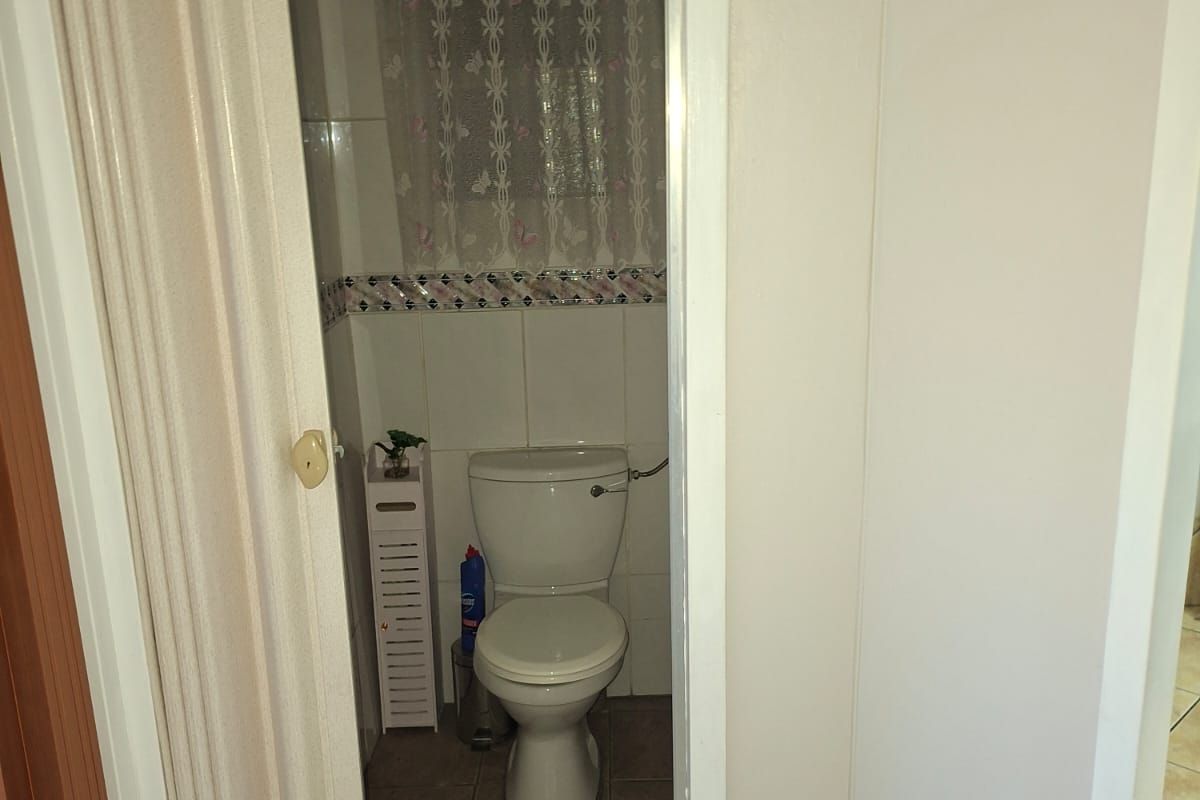 A compact bathroom featuring a standard toilet, tiled flooring, and a folding door entrance.