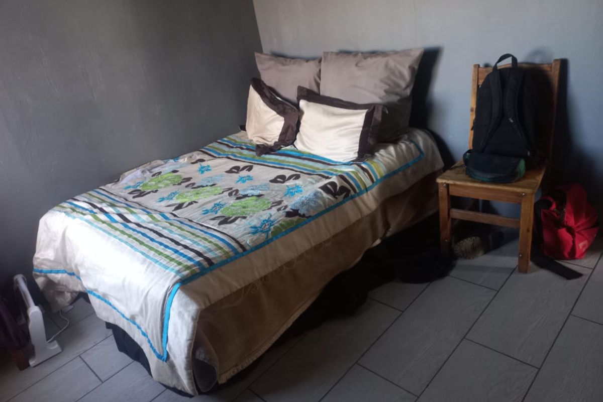 A bedroom featuring tiled flooring and neutral wall finishes, providing a functional space for rest.