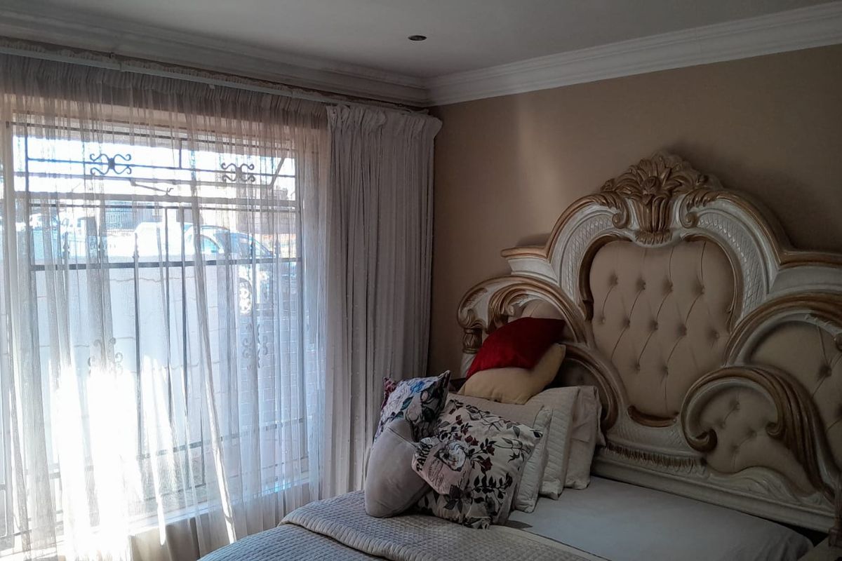 A bedroom featuring a large window with security bars and decorative crown molding.
