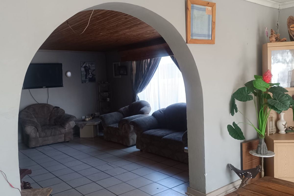 A living room area featuring a distinctive arched entryway, tiled flooring, and a timber-paneled ceiling, creating a cozy and traditional atmosphere.