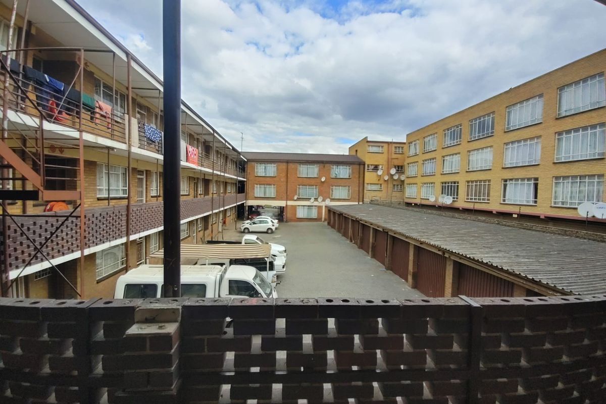 View of the apartment complex courtyard featuring brick facade buildings, multiple garage units, and open parking area.