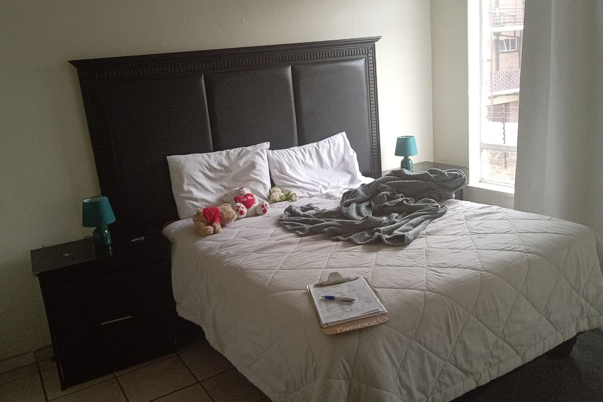 A bedroom featuring tiled flooring and a large window, providing a functional space for rest.