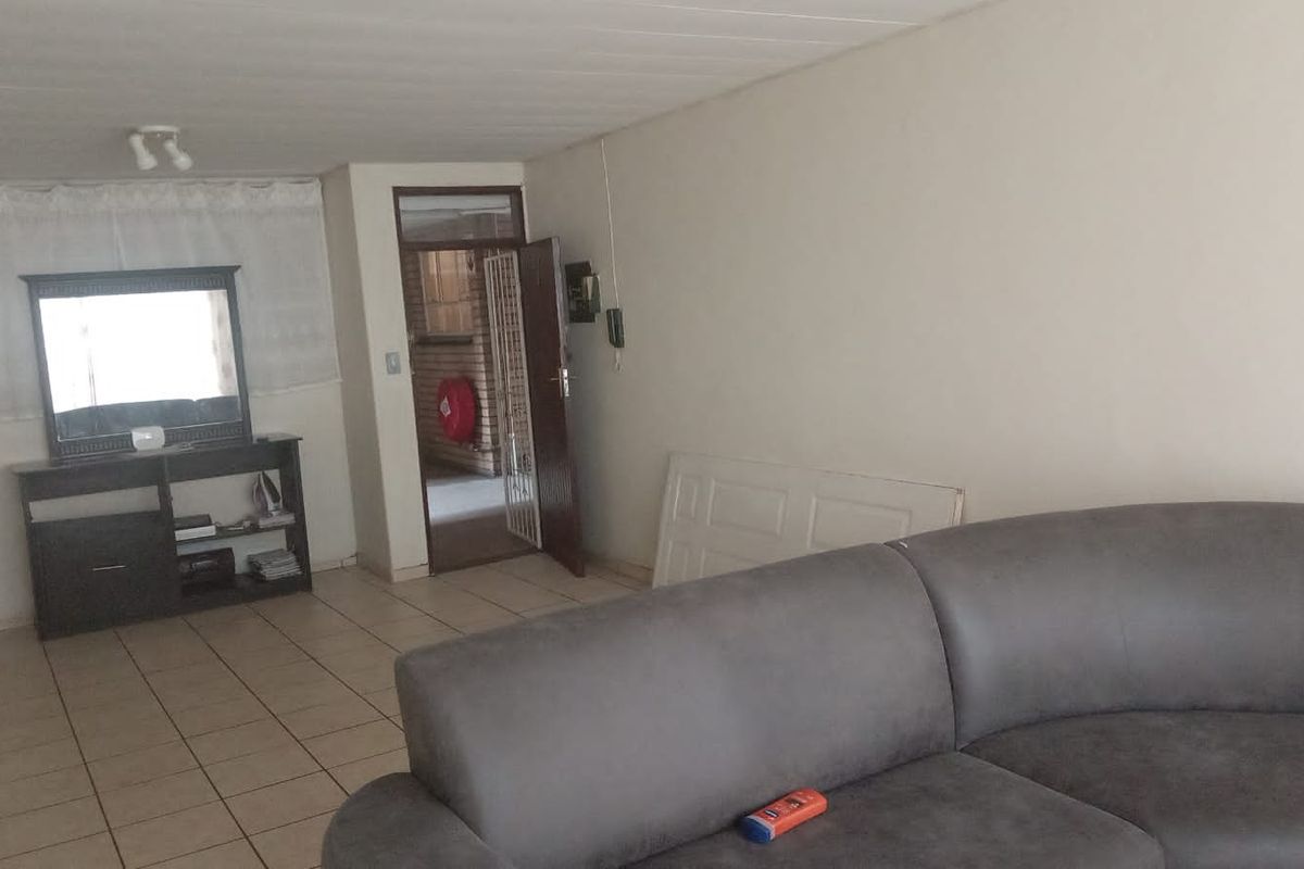 A living room area featuring tiled flooring and a doorway leading to an exterior space, providing a functional layout for the flat.