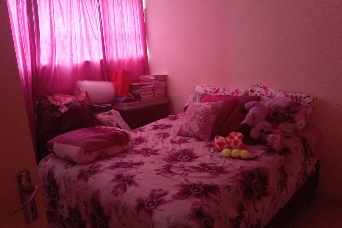 A bedroom featuring a window with pink curtains and tiled flooring.