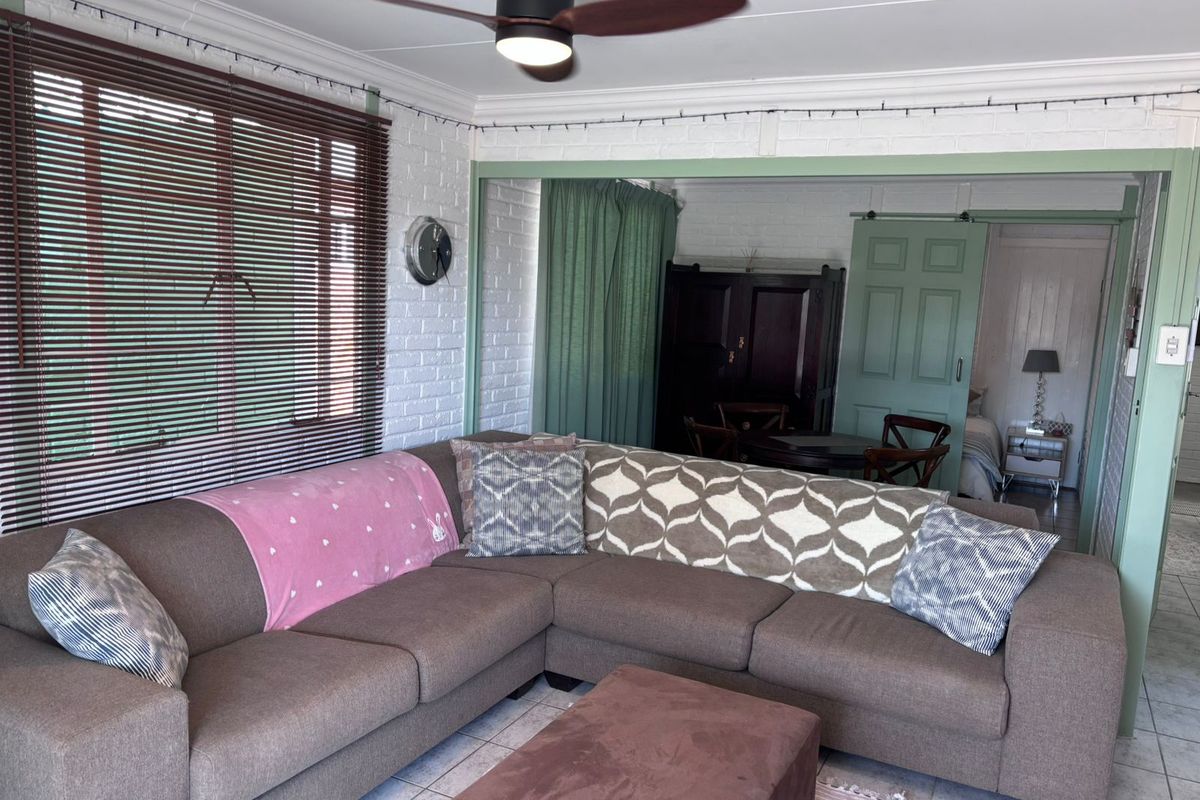 A comfortable living area featuring painted brick walls, tiled flooring, a ceiling fan, and a sliding barn-style door leading to an adjacent room.