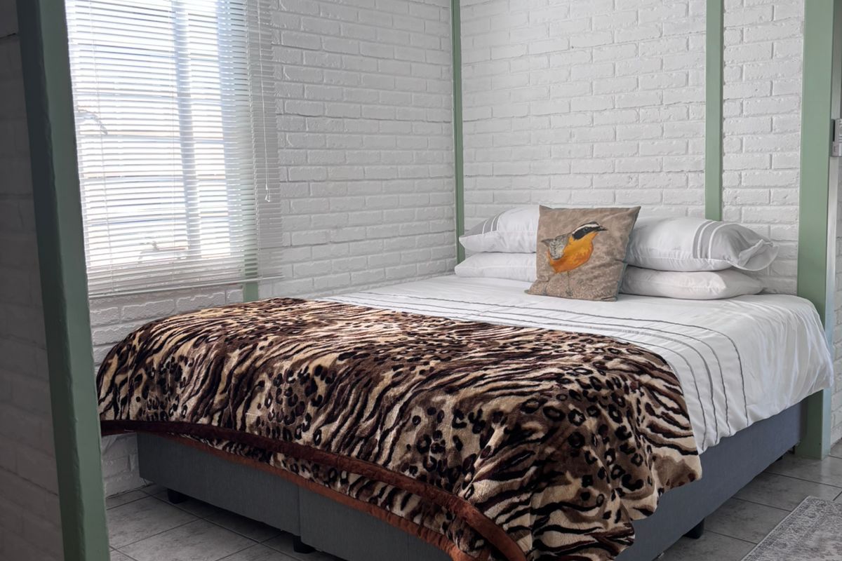 A well-maintained bedroom featuring painted brick walls, tiled flooring, and a ceiling fan.