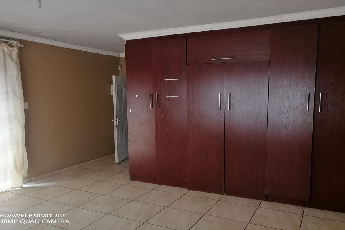 A bedroom featuring built-in dark wood cabinetry, tiled flooring, and decorative ceiling cornicing.