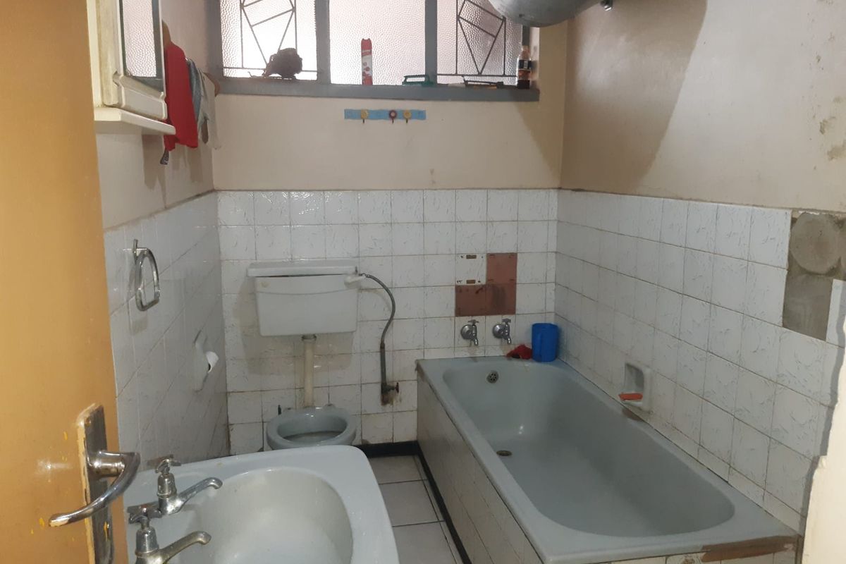 A dated bathroom featuring a standard bathtub, pedestal basin, and toilet, requiring significant renovation and modernization of finishes and fixtures.
