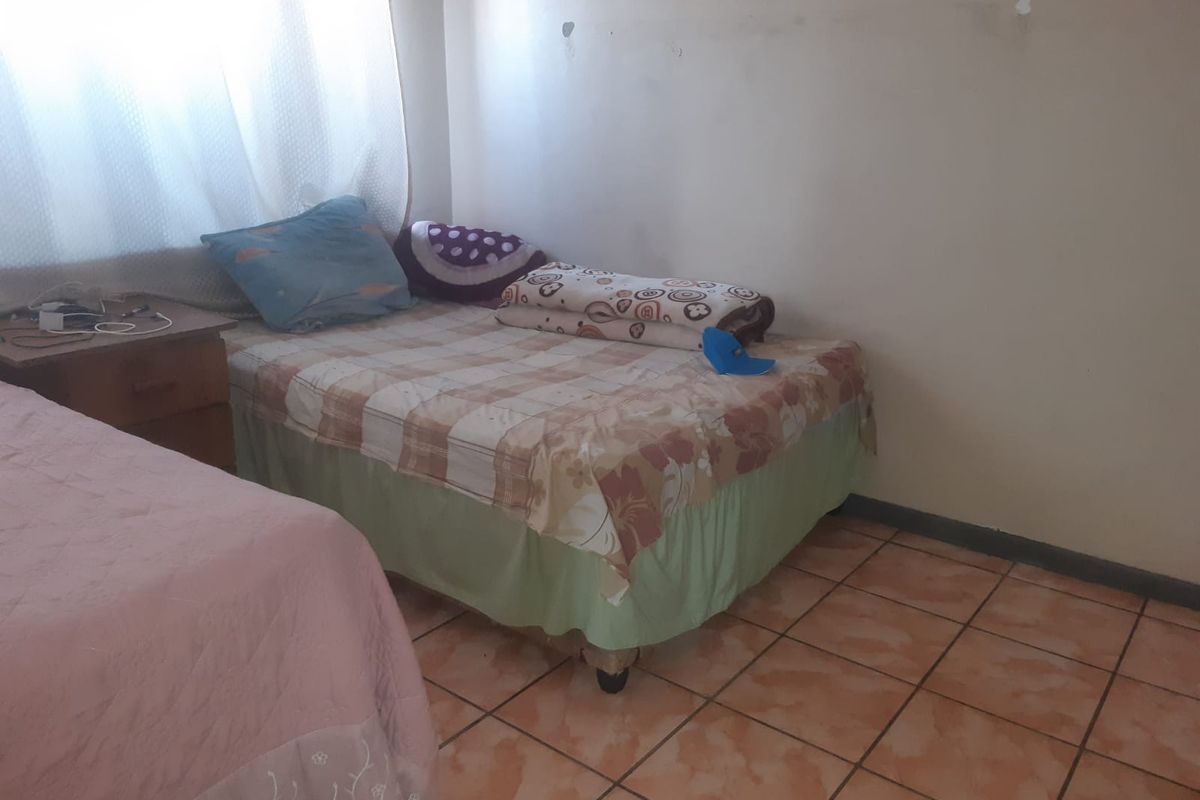 A bedroom featuring tiled flooring and neutral wall finishes, providing a functional space for rest.