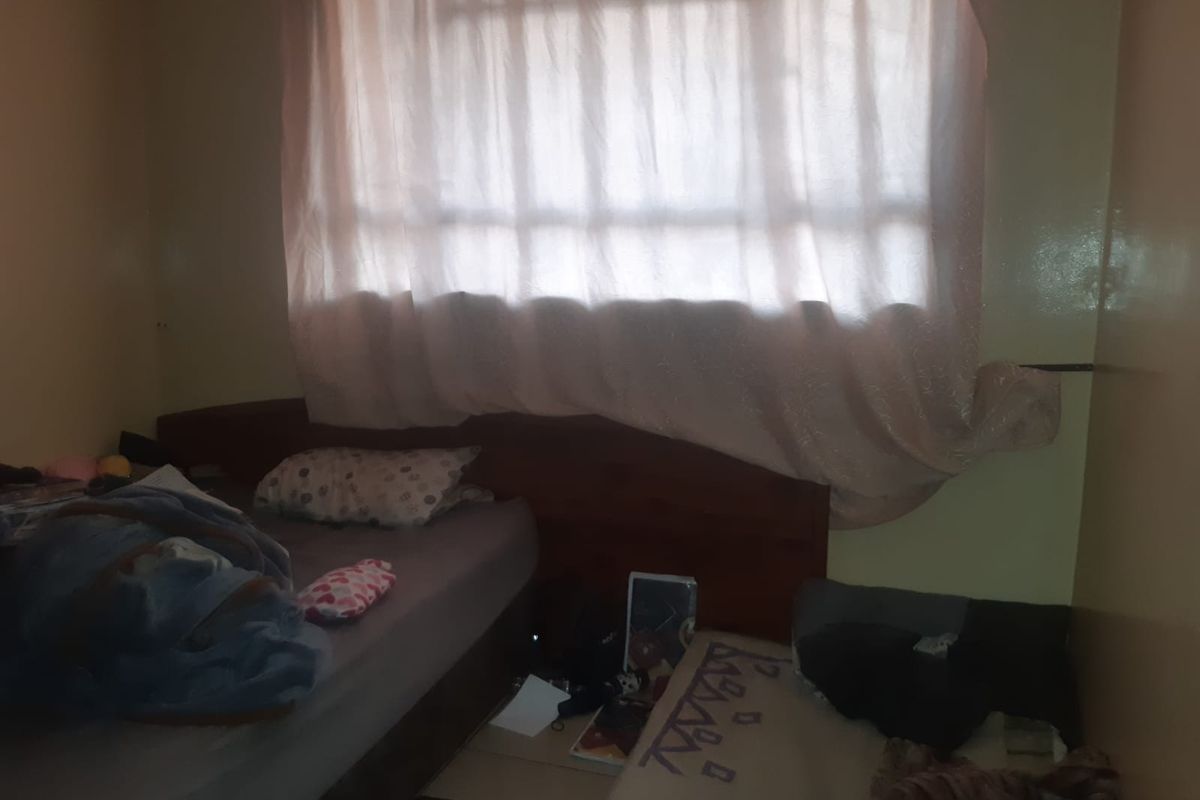 A bedroom featuring a window with curtains and built-in headboard structure.