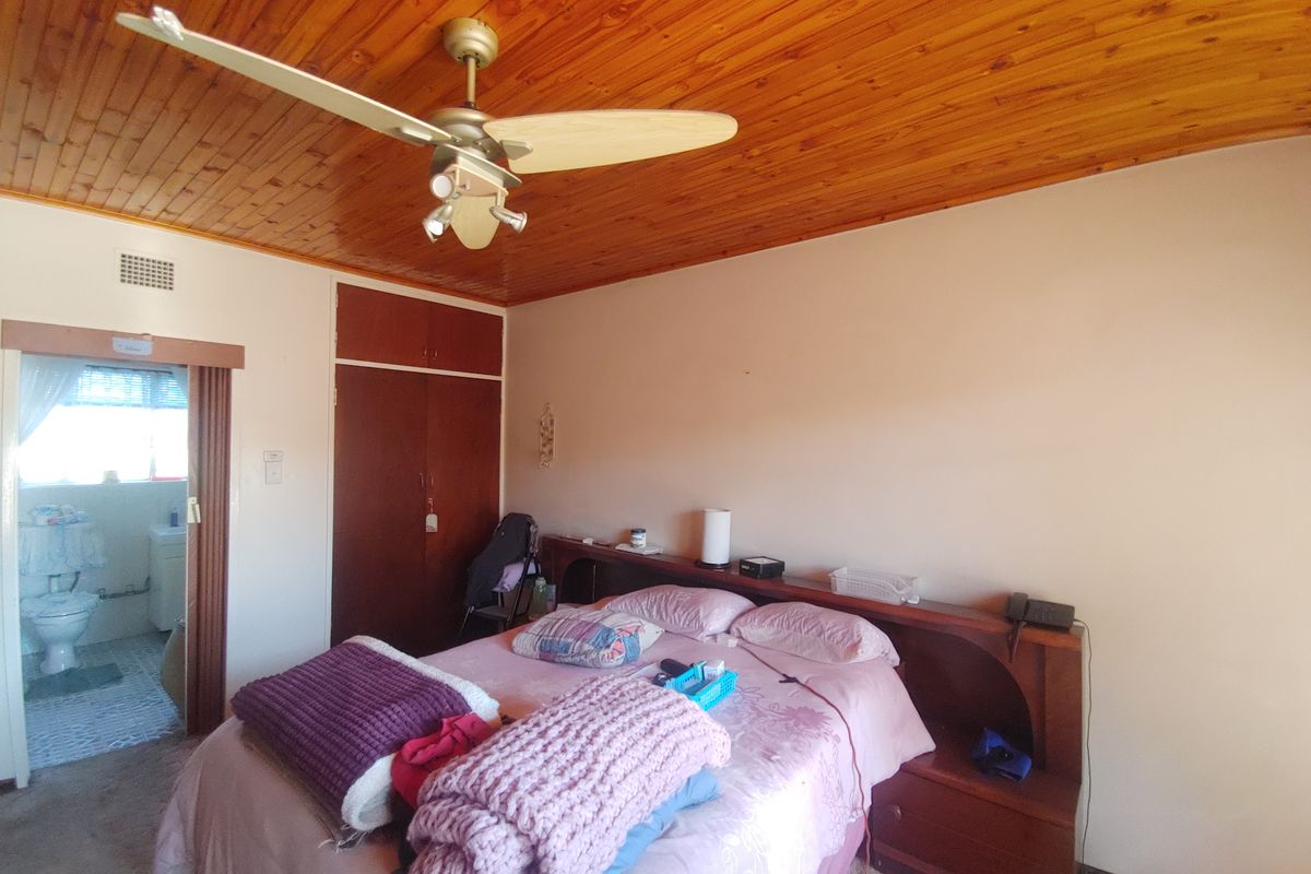 A bedroom featuring a timber-clad ceiling, built-in wooden cabinetry, and an attached en-suite bathroom.