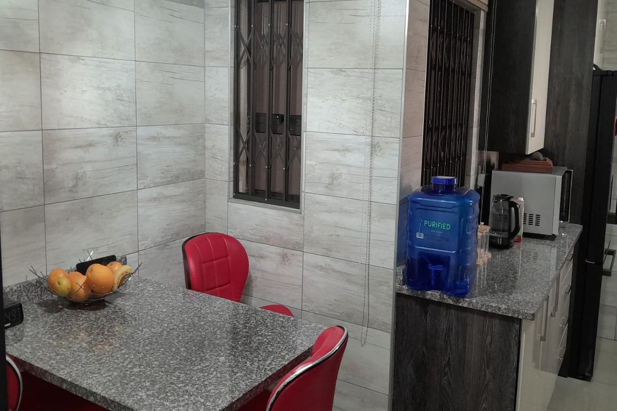 A functional kitchen area featuring granite countertops, tiled walls, and built-in cabinetry with a breakfast nook.