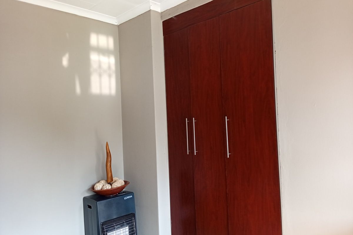 A bedroom interior featuring built-in wooden cabinetry with modern handles and neutral wall finishes.
