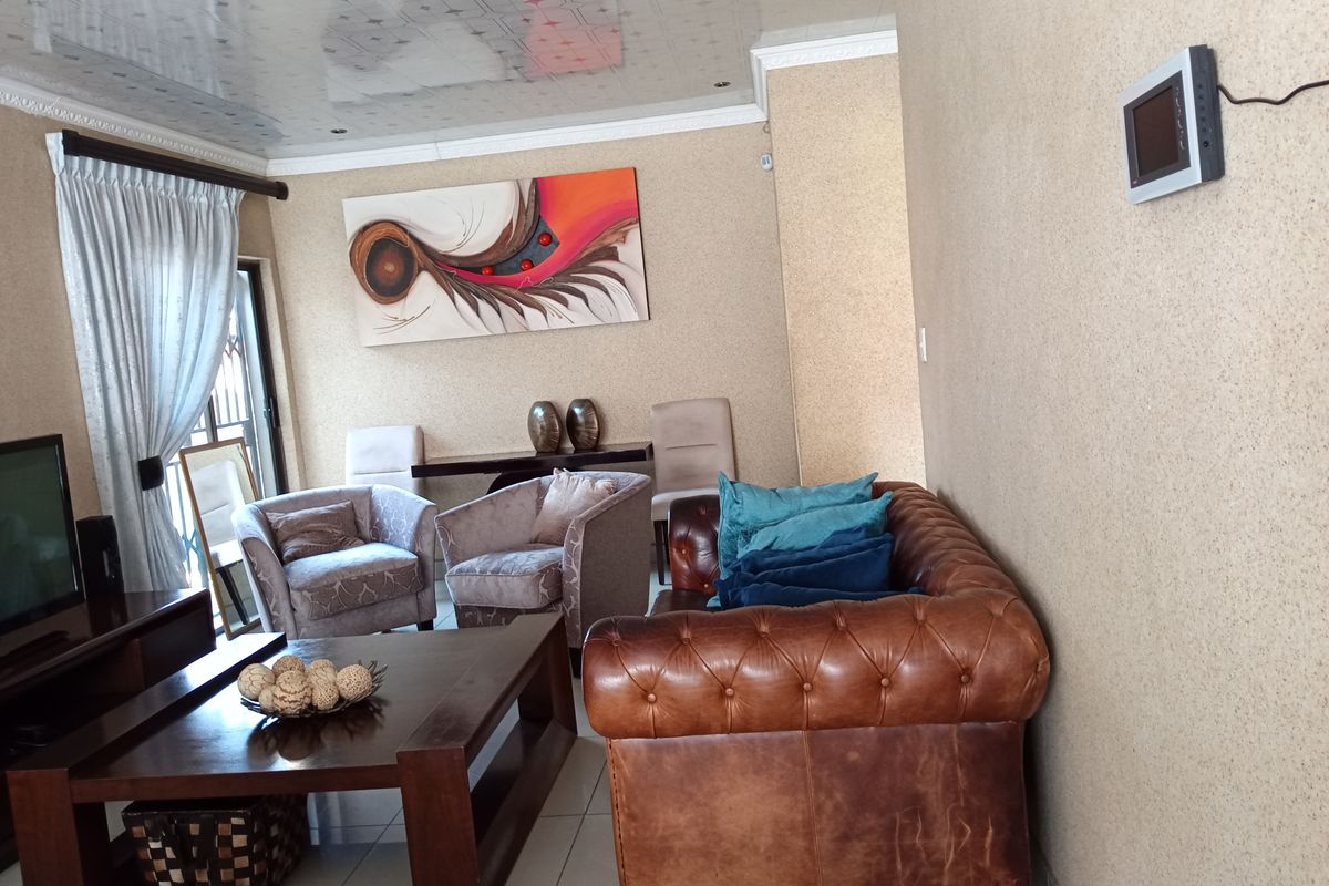 A comfortable living room featuring tiled flooring, textured wall finishes, and a wall-mounted security intercom system.