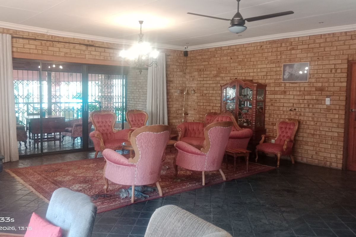 Spacious living room featuring exposed brick walls, slate tile flooring, a ceiling fan, and large sliding glass doors leading to an outdoor patio area.