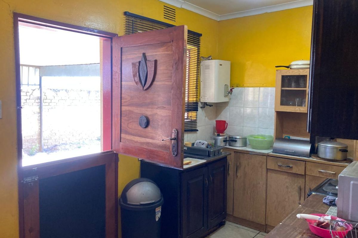 A functional kitchen featuring wooden cabinetry, tiled splashbacks, and a stable-style door providing direct access to the exterior.