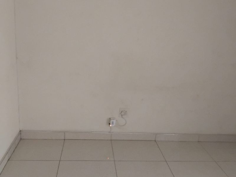 An empty bedroom featuring neutral tiled flooring and plain walls, providing a blank canvas for personalization.