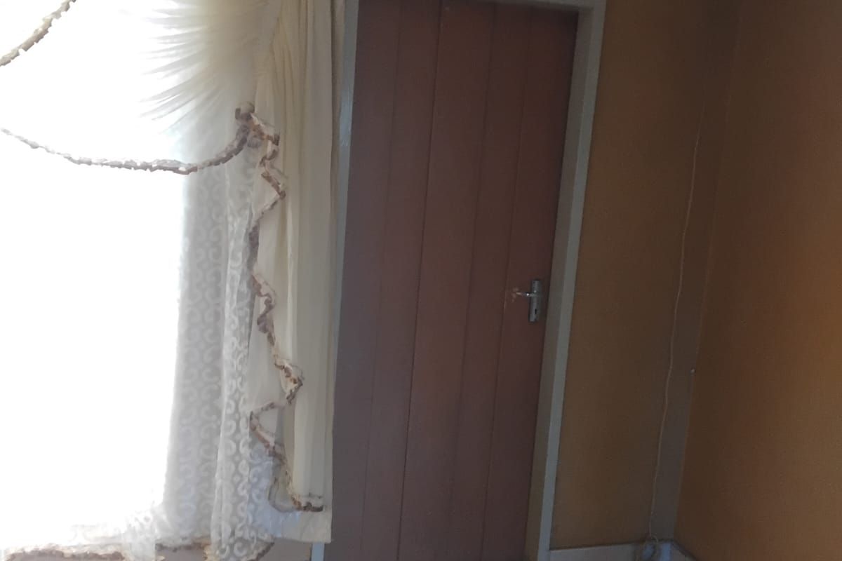 A simple interior living space featuring tiled flooring and a standard internal door, currently vacant and ready for updates.