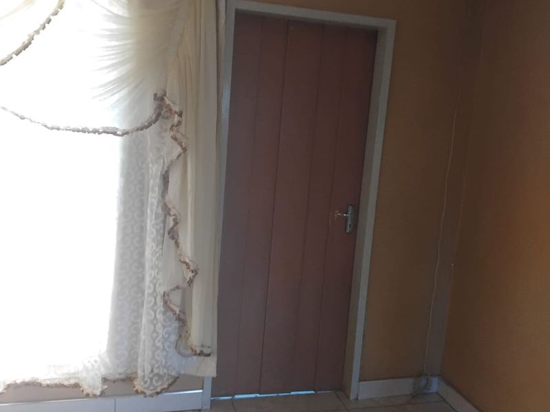 A simple interior living space featuring tiled flooring and a standard internal door, currently vacant and ready for updates.