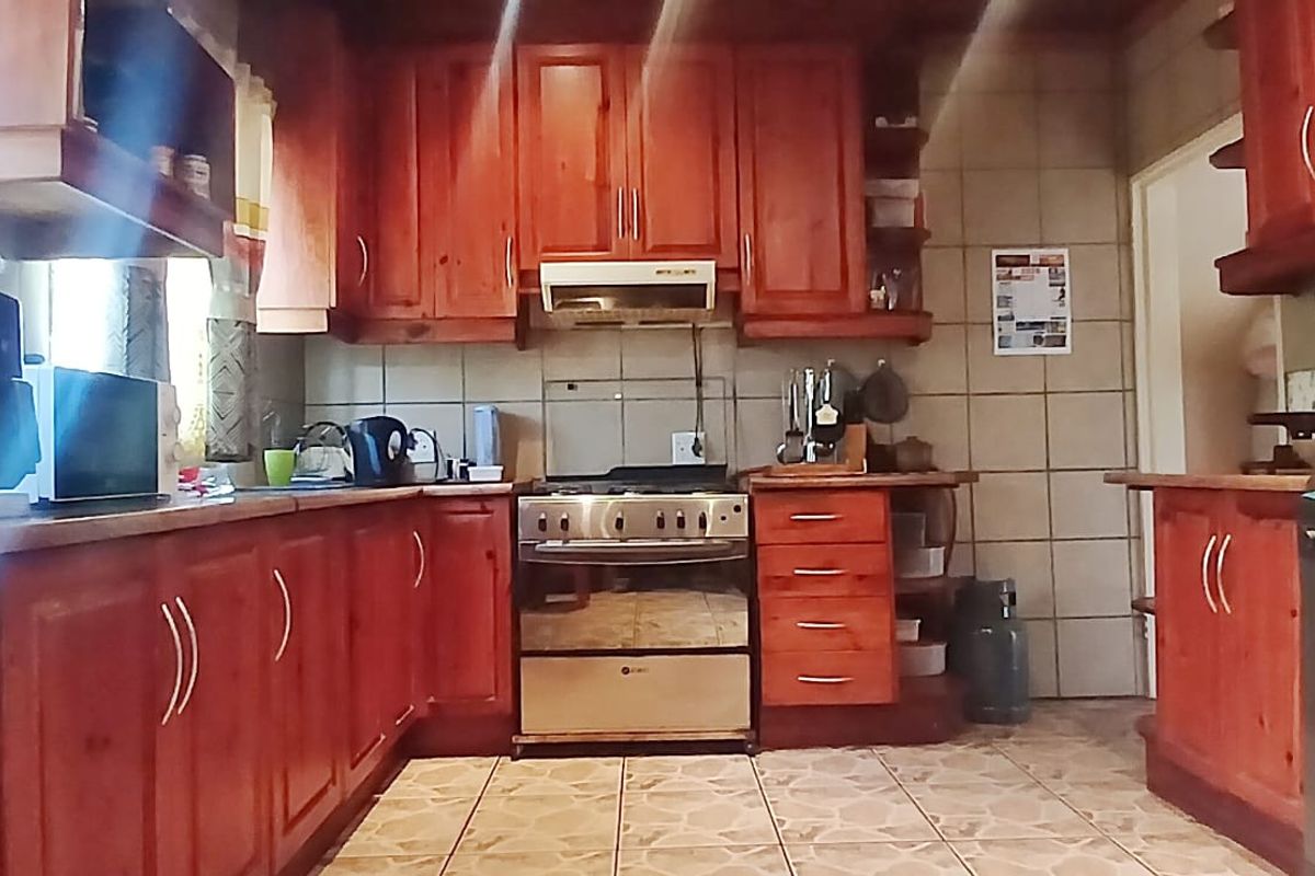 A functional kitchen featuring solid wood cabinetry, tiled splashbacks, and a freestanding gas stove with an integrated extractor fan.