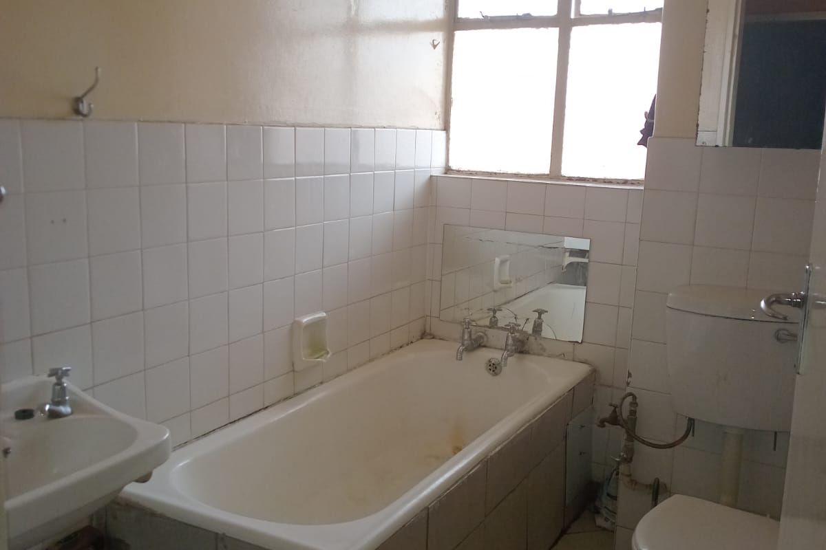 A dated bathroom featuring a standard bathtub, pedestal basin, and toilet with original wall tiling and floor tiles.