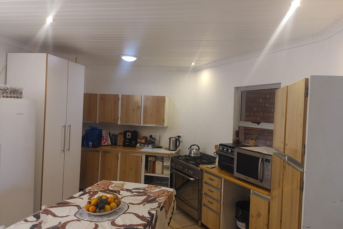 A functional kitchen featuring wooden cabinetry, a gas stove, and tiled flooring, offering a practical layout for daily meal preparation.