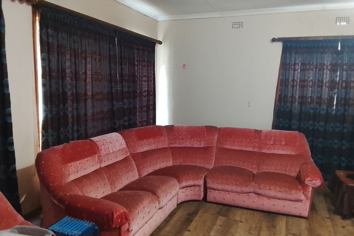 A living room featuring wood-look flooring, neutral walls, and curtained windows, providing a functional and comfortable space for relaxation.