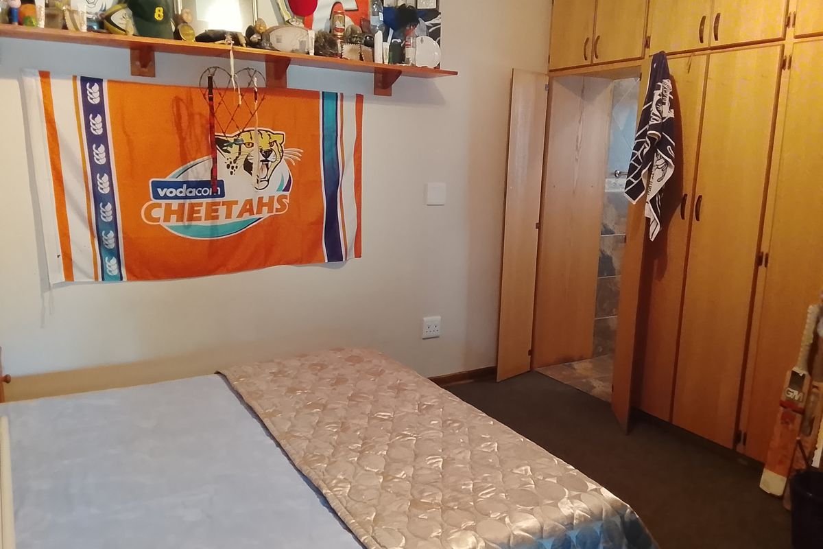 A bedroom featuring built-in wooden cupboards and an en-suite bathroom access point.