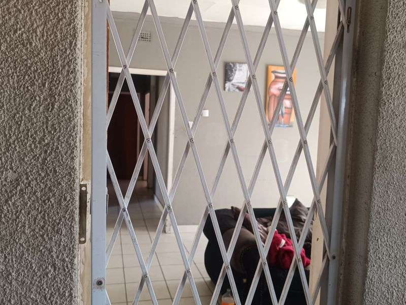 An entryway featuring a white retractable security gate leading into a tiled living area.