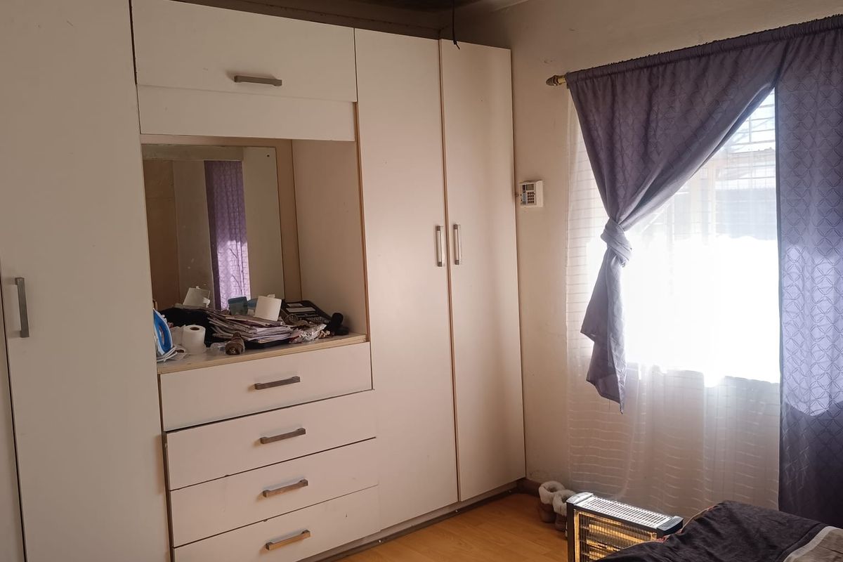 Bedroom featuring built-in cupboards, laminate flooring, and a ceiling fan. The ceiling shows visible signs of water damage and requires maintenance.