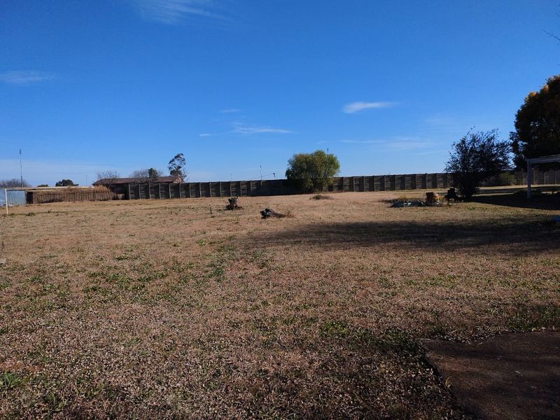 A spacious, level residential plot featuring established perimeter fencing and open grassed areas, suitable for future development.