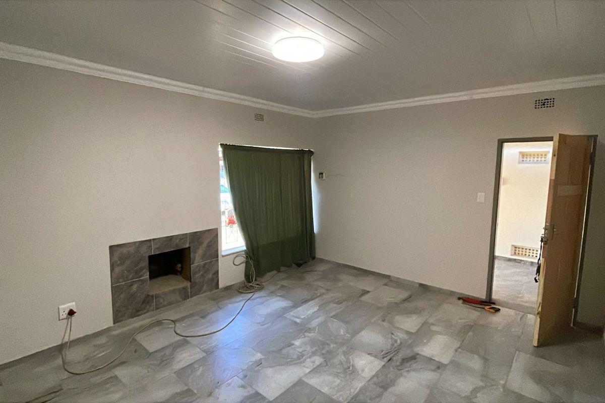 An empty living room featuring tiled flooring, a built-in fireplace, and coved ceilings, offering a blank canvas for interior design.