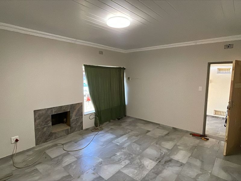 An empty living room featuring tiled flooring, a built-in fireplace, and coved ceilings, offering a blank canvas for interior design.