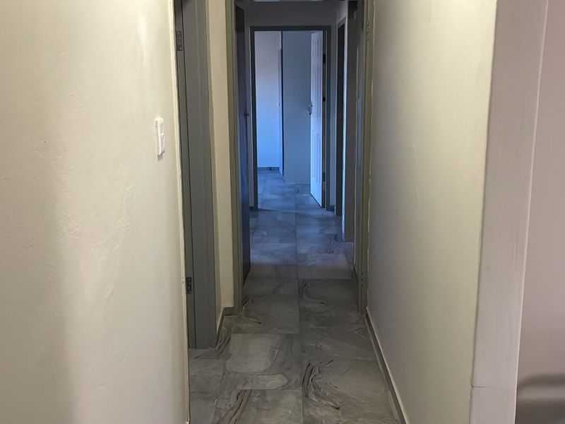 A functional hallway featuring neutral tiled flooring and multiple internal doorways, providing access to various rooms within the home.