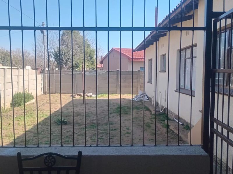 A view of the rear yard featuring a precast concrete boundary wall, security bars, and a tiled roof house exterior.