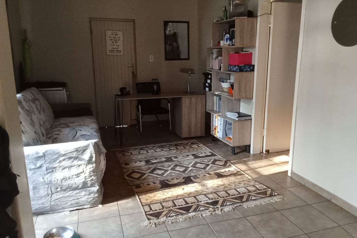 A functional living area featuring tiled flooring and neutral wall finishes, providing a versatile space for relaxation or home office use.