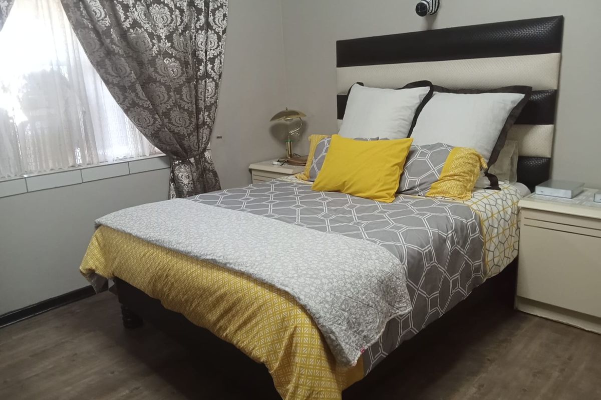 A bedroom featuring laminate flooring and a built-in headboard, providing a functional and comfortable sleeping space.