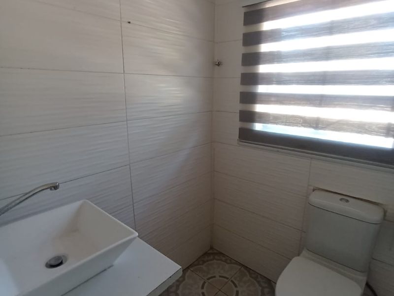A compact bathroom featuring a modern vessel sink on a vanity cabinet, a standard toilet, and decorative patterned floor tiles.