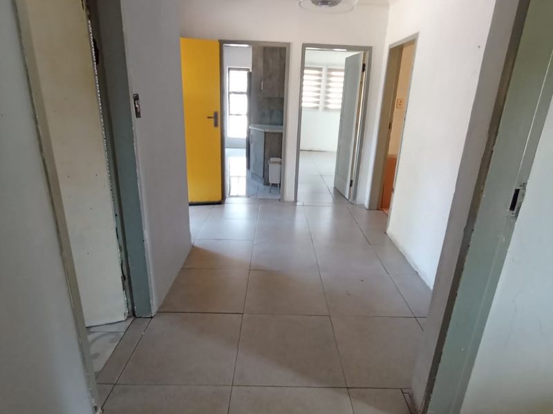 A functional hallway featuring neutral tiled flooring and multiple internal doorways providing access to various rooms within the home.